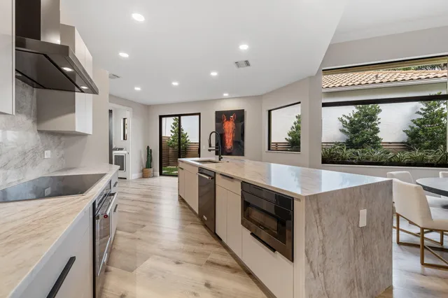 a large kitchen with stainless steel appliances granite countertop a large counter top a stove and a sink