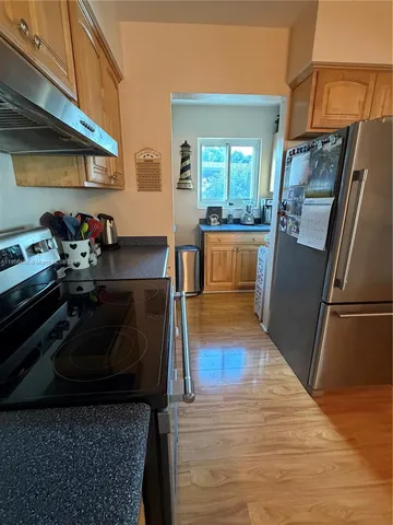 a kitchen with granite countertop a refrigerator stove and wooden floor