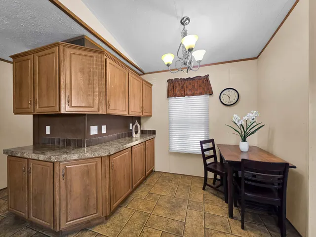 a living room with couches a dining table and a chandelier with kitchen view