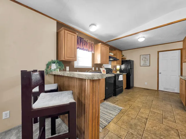 a kitchen with stainless steel appliances granite countertop a refrigerator a sink dishwasher a stove with white cabinets and wooden floor