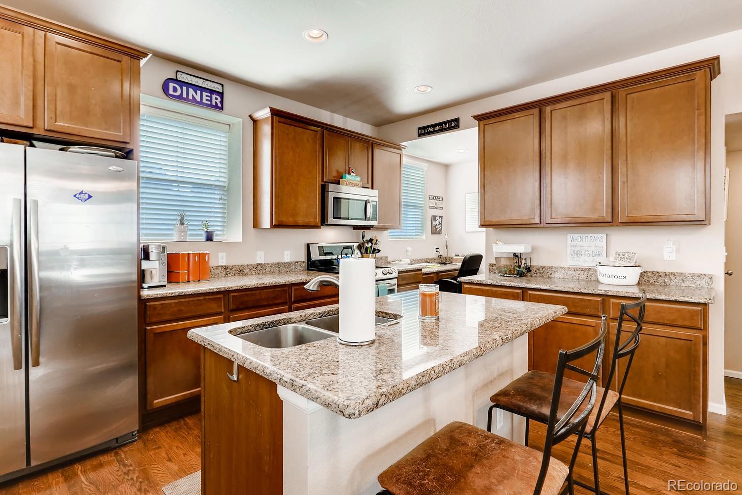 9520 Halstead Lane Lone Tree, CO 80124 - Photo 4 of 20 a kitchen with stainless steel appliances granite countertop a refrigerator a stove and a sink with wooden cabinets