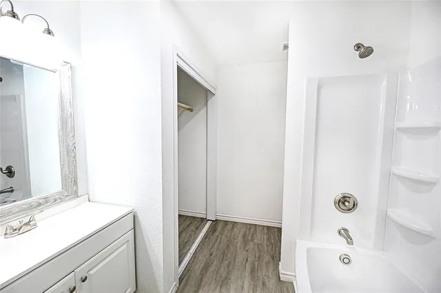 an empty room with wooden floor cabinet and windows