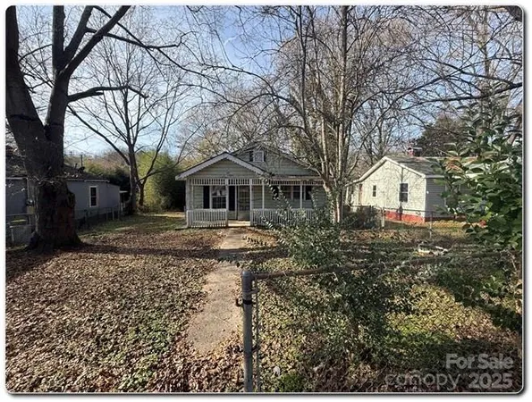 a backyard of a house with large trees and barbeque oven