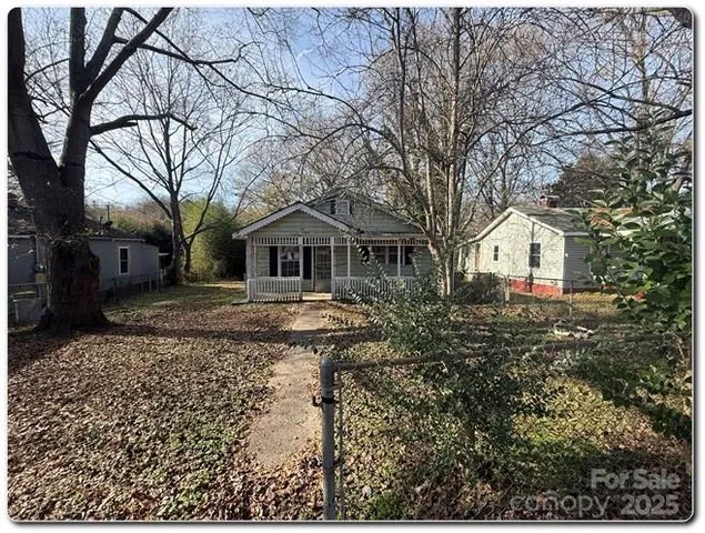 a backyard of a house with large trees and barbeque oven