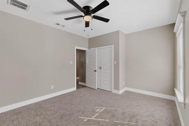 an empty room with a ceiling fan and carpet