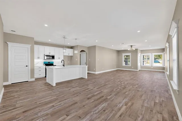 a view of a big room with wooden floor and windows