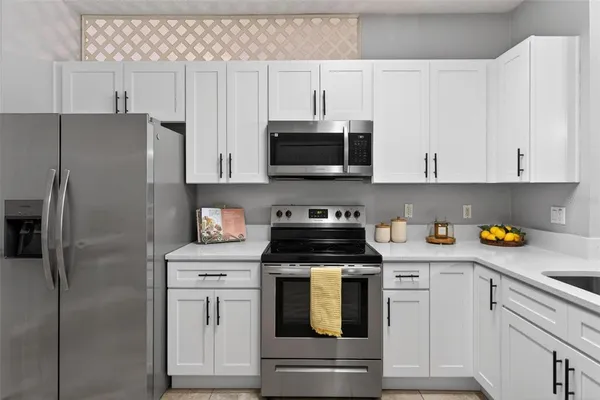 a kitchen with stainless steel appliances granite countertop white cabinets a refrigerator a stove a sink and white cabinets