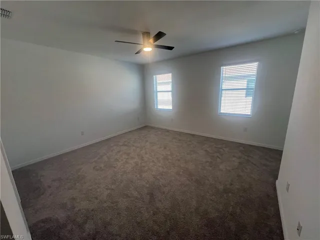 an empty room with windows and chandelier fan