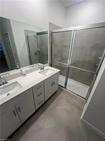 a spacious bathroom with a double vanity sink a mirror and a shower