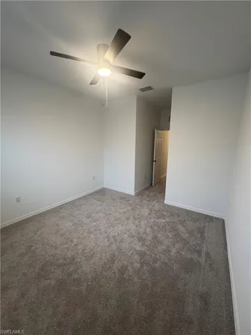 a view of an empty room and chandelier fan