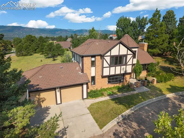 a view of a big house with a yard plants and large tree