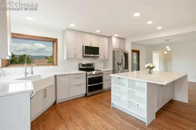 a large kitchen with stainless steel appliances a sink and cabinets