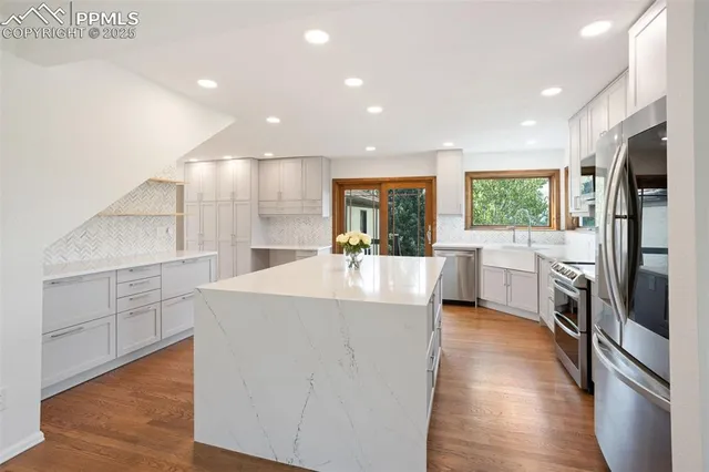 a large kitchen with stainless steel appliances a large counter top and a refrigerator
