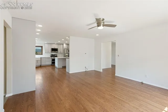 a view of an empty room with kitchen and window