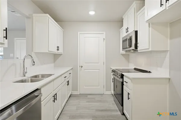 a kitchen with granite countertop white cabinets and white appliances