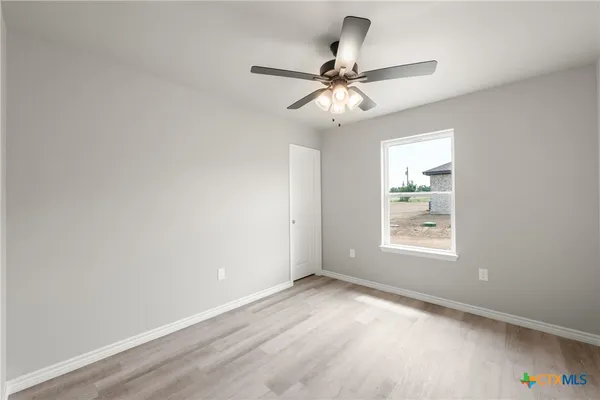 an empty room with a window and a fan