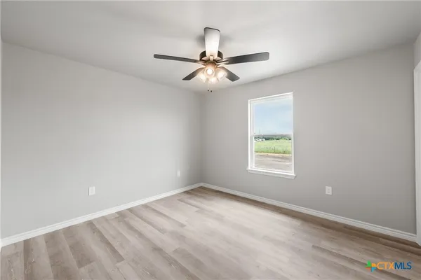 an empty room with a window and a fan