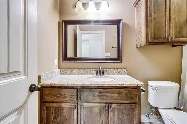a bathroom with a granite countertop bathtub shower sink vanity and toilet