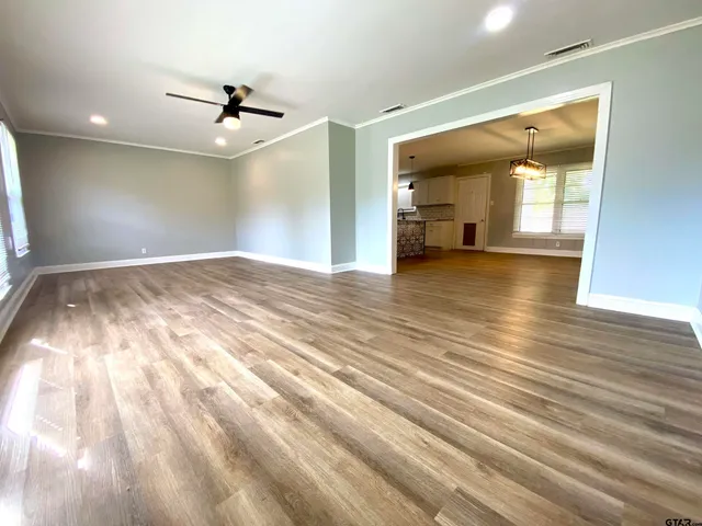 a view of empty room with wooden floor and fan