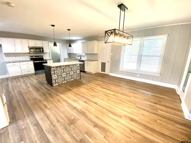 a open kitchen with granite countertop a stove a sink dishwasher and a fireplace with wooden floor
