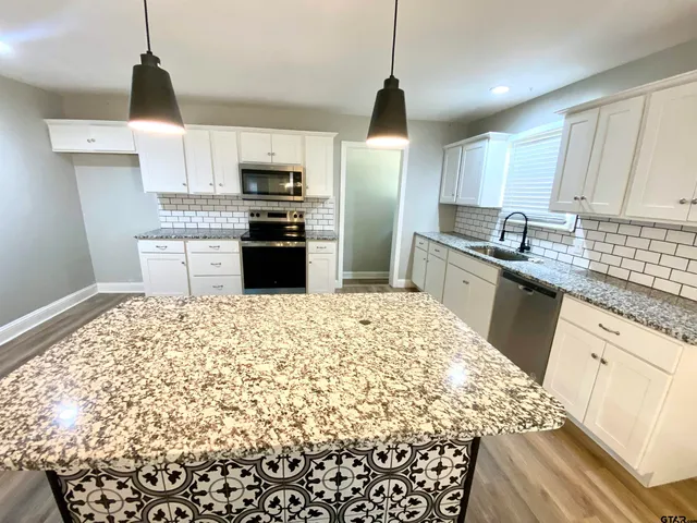 a kitchen with granite countertop white cabinets and stainless steel appliances