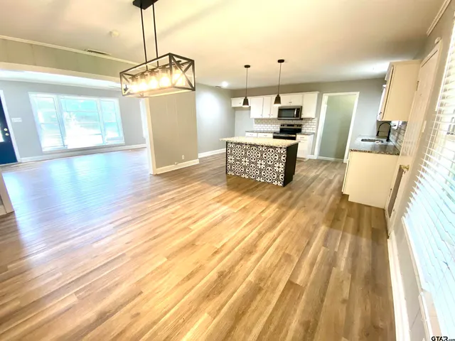 a living room with stainless steel appliances kitchen island granite countertop furniture and a fireplace