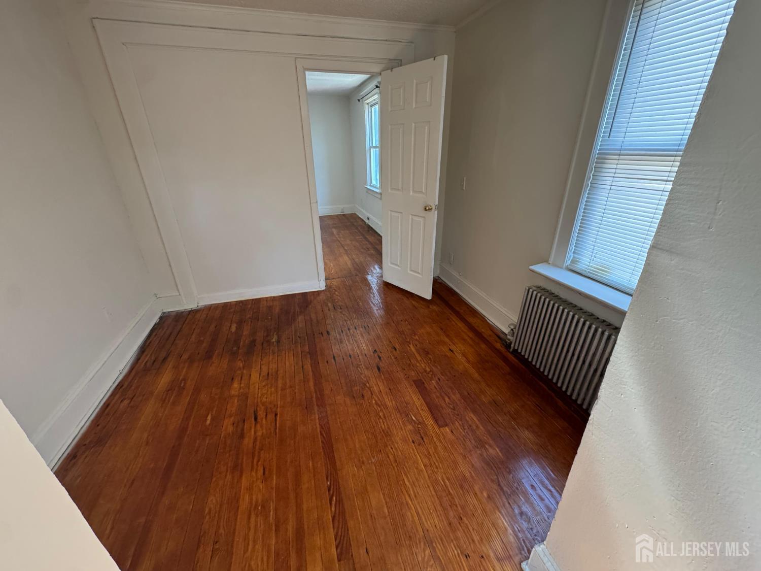 110 Rector Street, Unit 2 Perth Amboy, NJ 08861 - Photo 4 of 11 a view of an empty room with wooden floor and a window
