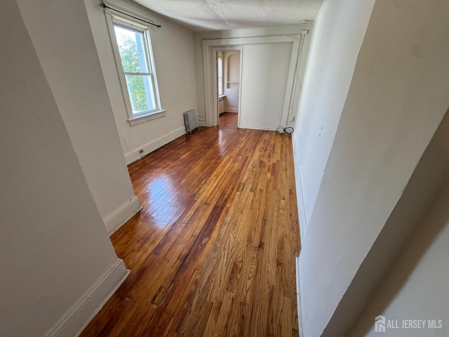 110 Rector Street, Unit 2 Perth Amboy, NJ 08861 - Photo 7 of 11 a view of an empty room with wooden floor and a window