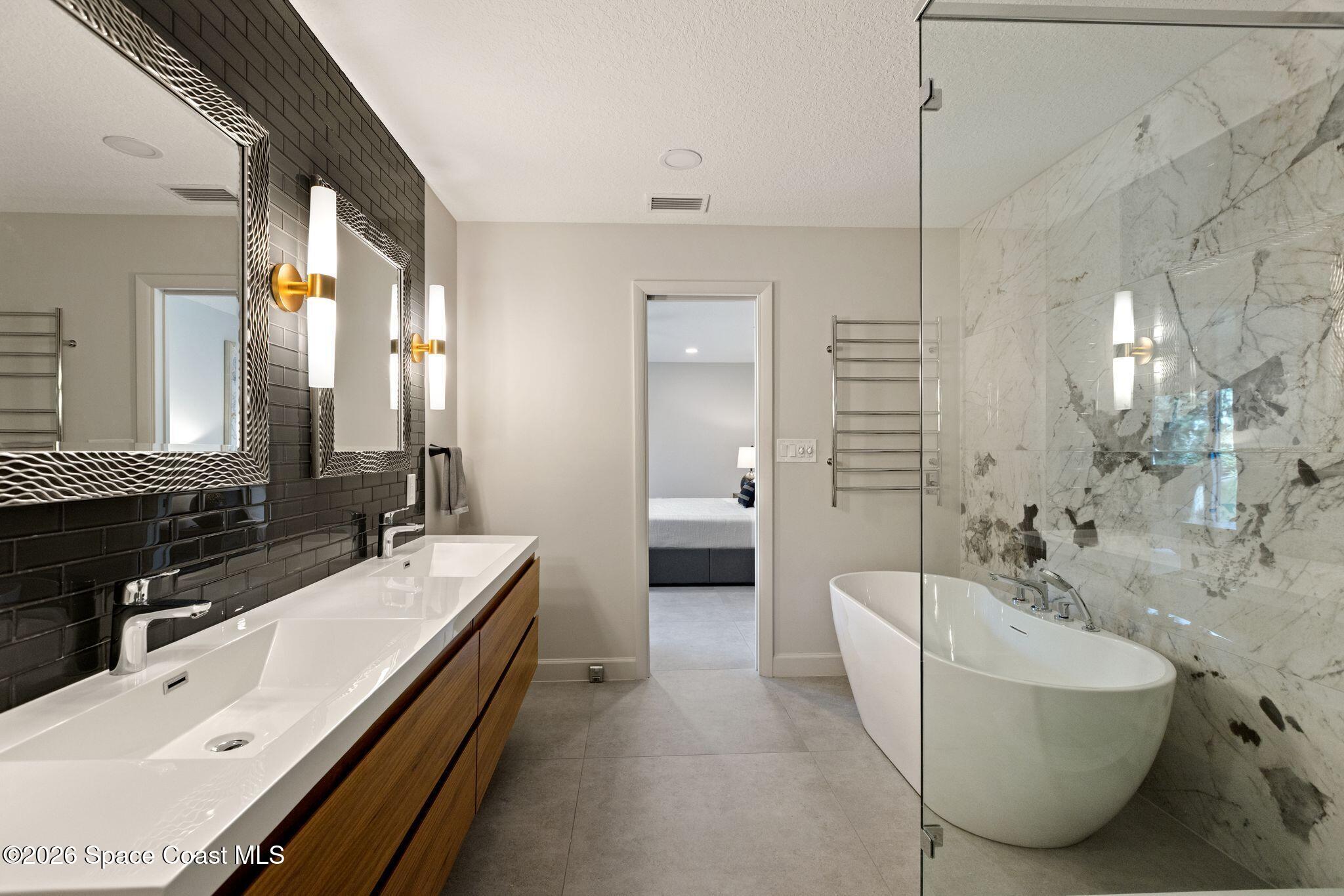 1224 Samar Road Cocoa Beach, FL 32931 - Photo 20 of 56 a bathroom with a double vanity sink a large mirror and a bathtub