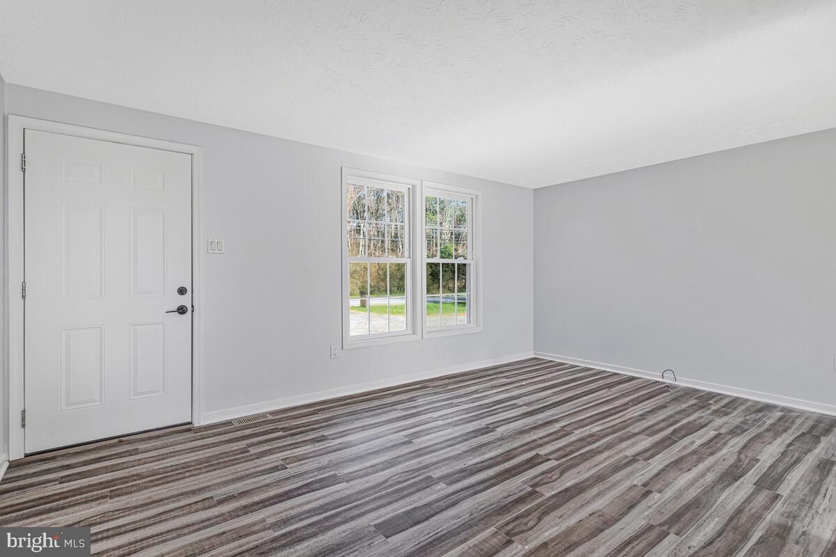 123 Cove Point Road Lusby, MD 20657 - Photo 7 of 38 a view of an empty room with wooden floor and a window