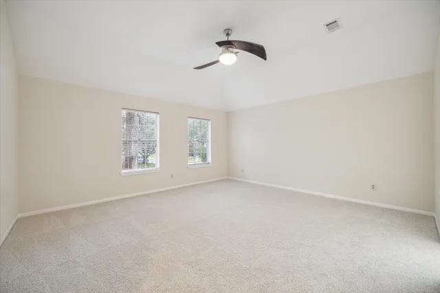 an empty room with windows and fan