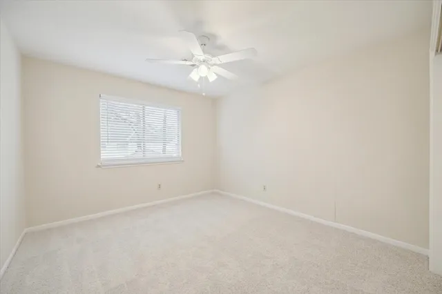 an empty room with a window and ceiling fan