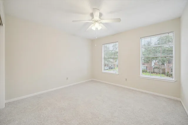 an empty room with a window and a ceiling fan