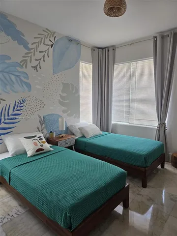 a bedroom with 2 bed and a window