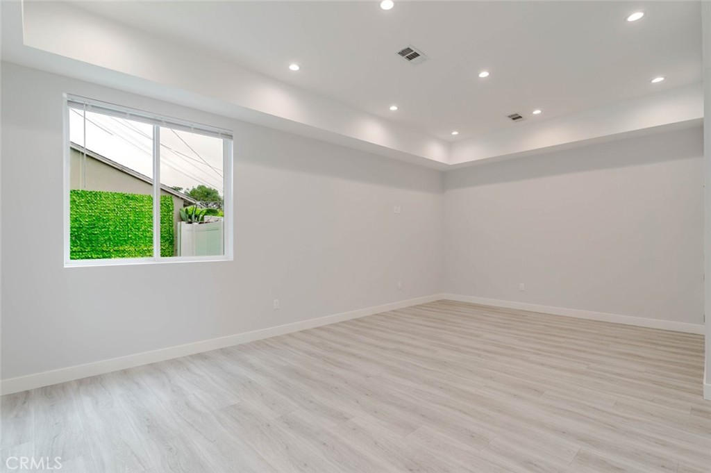 9035 Rathburn Avenue, Unit 1/2 Northridge, CA 91325 - Photo 5 of 25 an empty room with wooden floor and windows