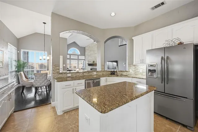 a kitchen with stainless steel appliances granite countertop a sink a stove and a refrigerator