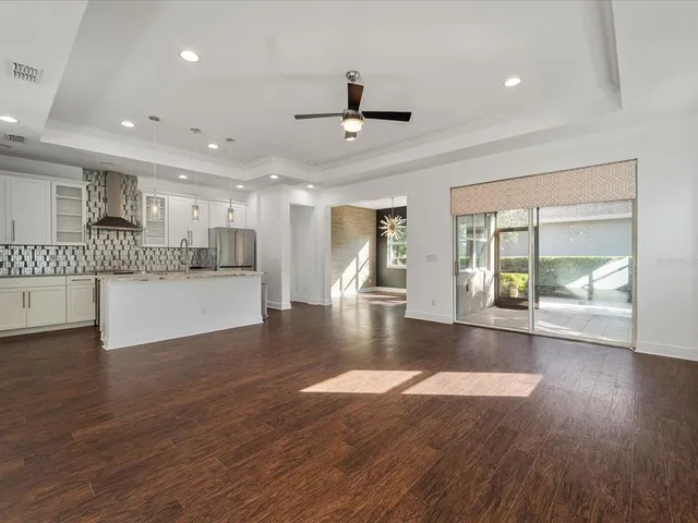 a view of an empty room with wooden floor and a kitchen