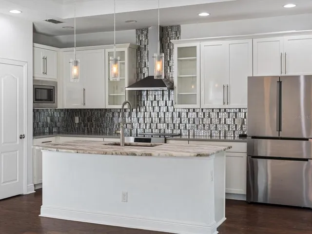 a kitchen with stainless steel appliances granite countertop a refrigerator a sink and white cabinets