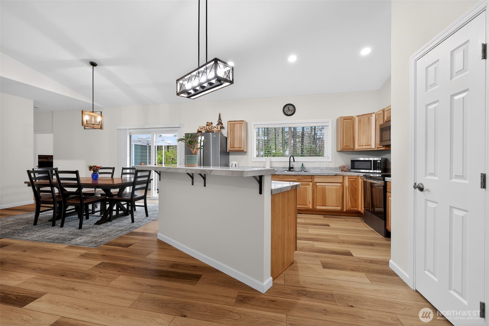 148 East Fox Run Lane Grapeview, WA 98546 - Photo 7 of 32 a kitchen with stainless steel appliances granite countertop a stove top oven a sink a dining table and chairs with wooden floor