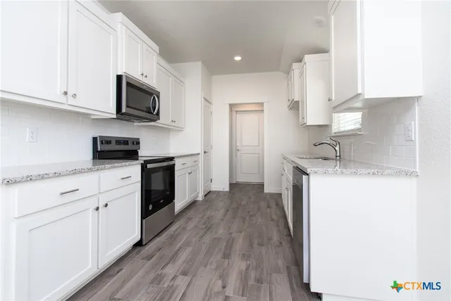 a kitchen with granite countertop white cabinets and white appliances