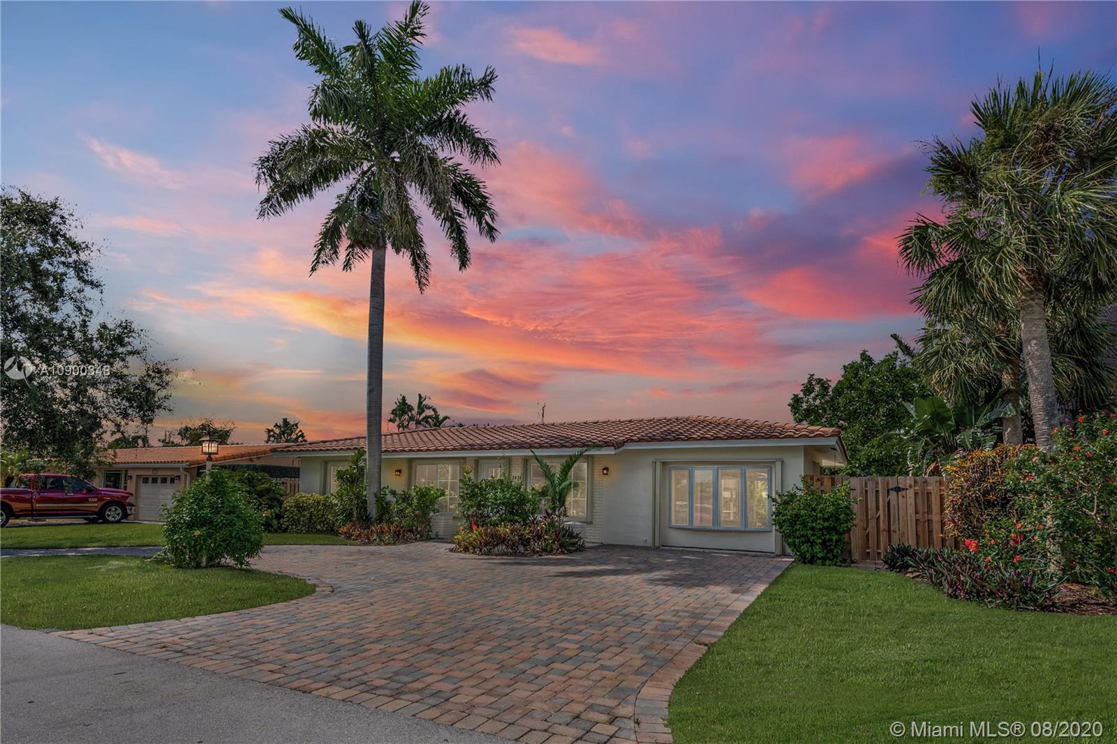2630 Northeast 51st Court Lighthouse Point, FL 33064 - Photo 1 of 43 a front view of a house with a garden and a yard