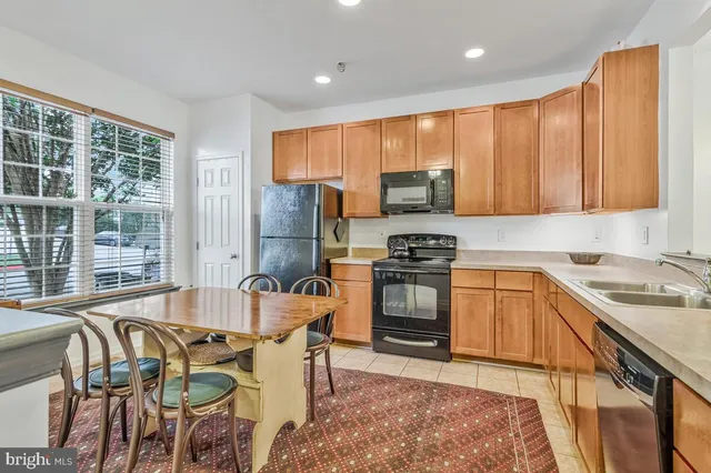 a kitchen with stainless steel appliances granite countertop a stove top oven a sink dishwasher a dining table and chairs with wooden floor