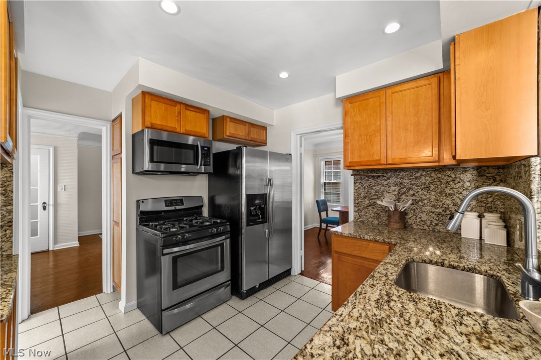 3806 Westwood Road University Heights, OH 44118 - Photo 11 of 41 Kitchen featuring stainless steel appliances, granite countertops, wood cabinetry, tile flooring, and recessed lighting
