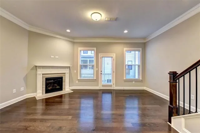 a view of an empty room with wooden floor fireplace and a window