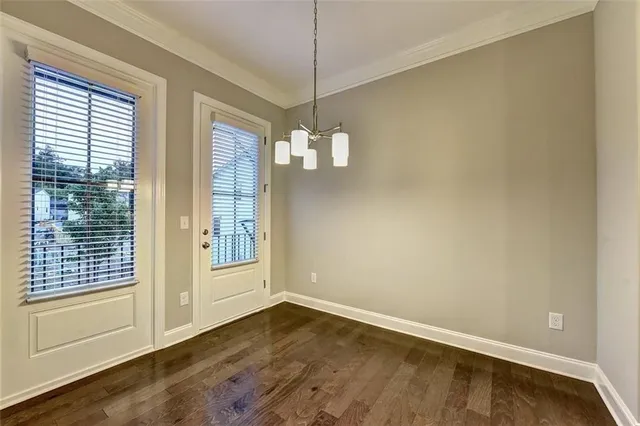 a view of an empty room with a window and hardwood floor