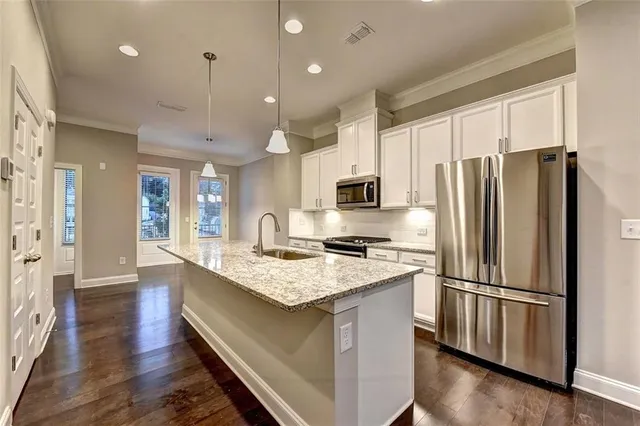 a kitchen with stainless steel appliances granite countertop a refrigerator a sink dishwasher a stove and a refrigerator with wooden floor