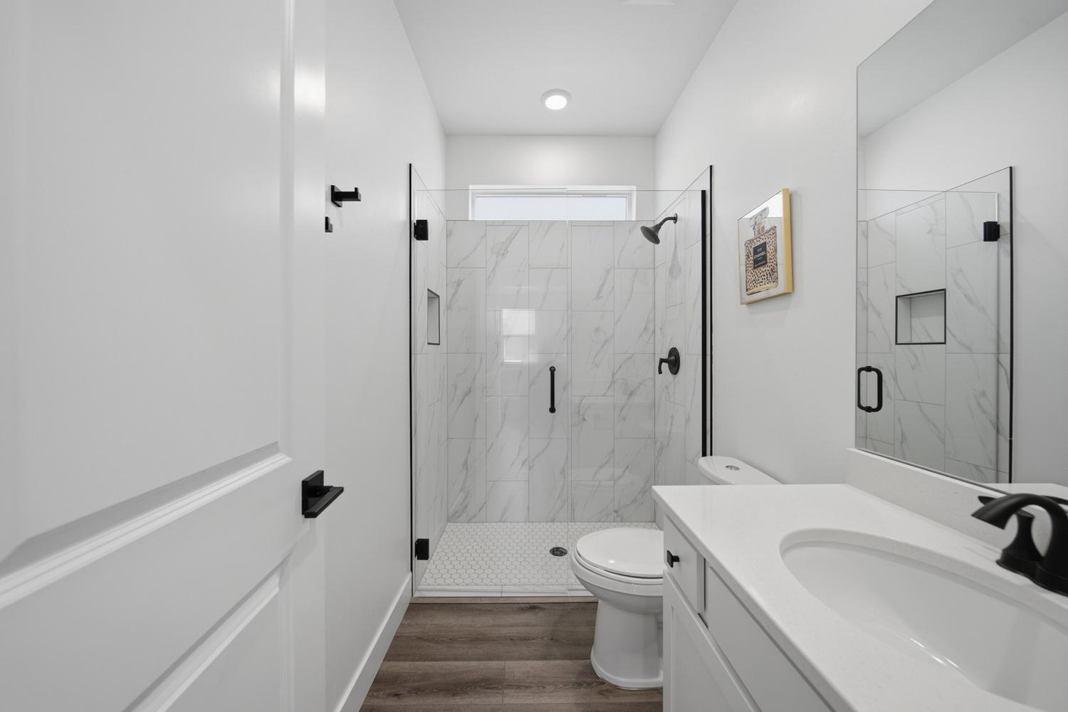 6144 Red Sand Lane St. George, UT 84790 - Photo 8 of 19 Spa-inspired and impeccably finished, this full bath features a frameless glass shower enclosed in marble-look tile from floor to ceiling. Matte-black fixtures and a transom window keep the palette crisp and contemporary, while the walk-in layout offers everyday function without sacrificing style.