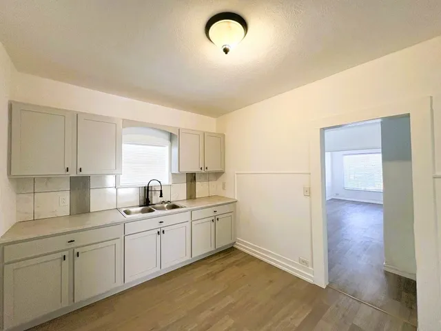 a kitchen with a sink cabinets and wooden floor