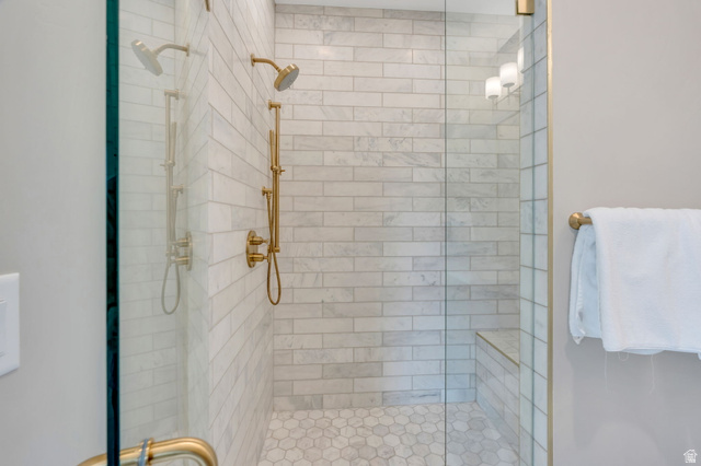 250 South Main Street, Unit 10 Alpine, UT 84004 - Photo 19 of 29 Glass-enclosed shower featuring white subway tile, a built-in bench, hexagonal floor tiles, a dual shower head system, and brass fixtures