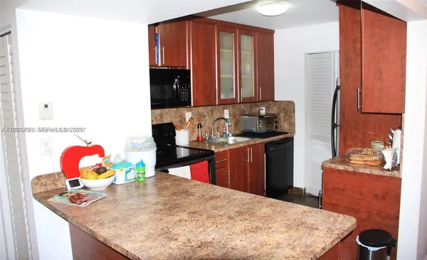 a kitchen with stainless steel appliances kitchen island granite countertop a sink dishwasher and a stove with wooden floor